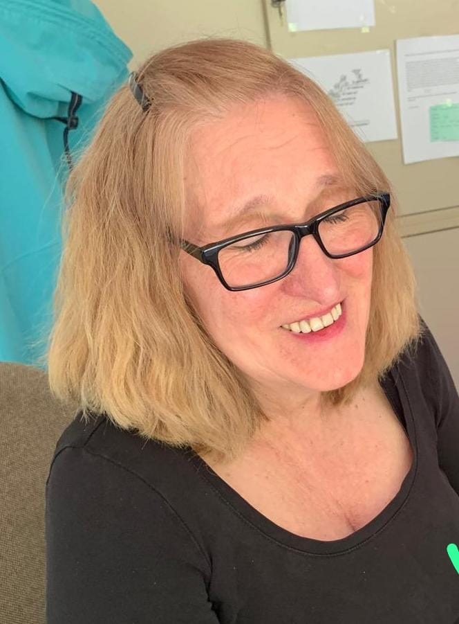 Porträt von Ute Schiemann, lächende Frau mit geschlossenen Augen, blonden schulterlangen Haaren und schwarzer Brille